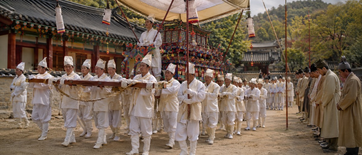 옛 한국 마을길에 놓인 전통 상여와 조용히 배웅하는 사람들의 모습